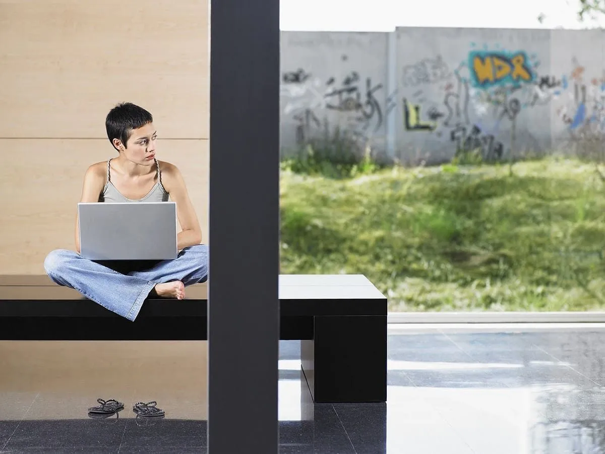 Person sitting by a window next to a graffiti wall
