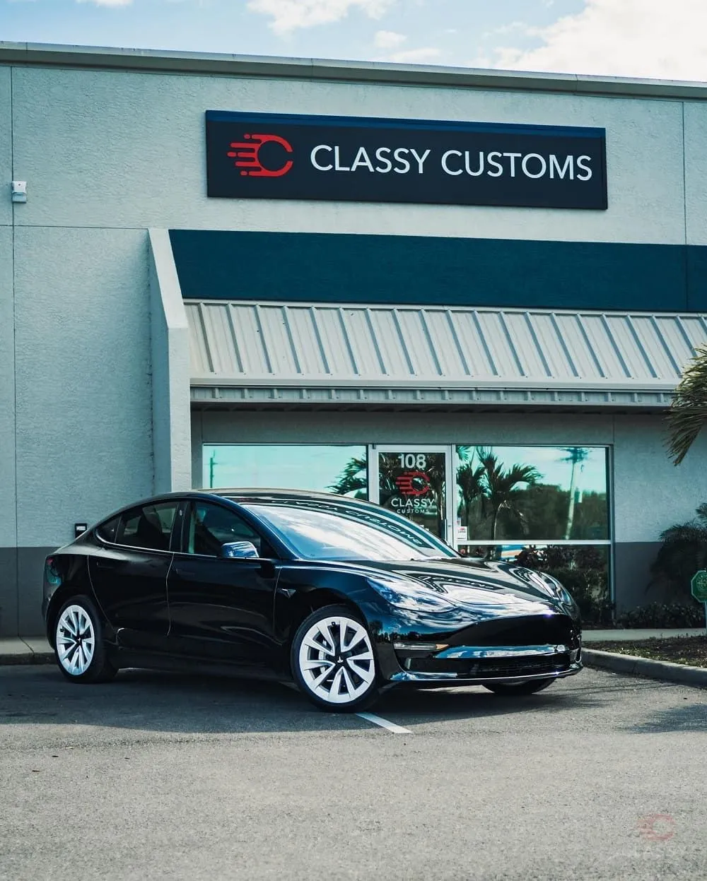 Black Tesla Model 3 parked in front of the Classy Customs shop