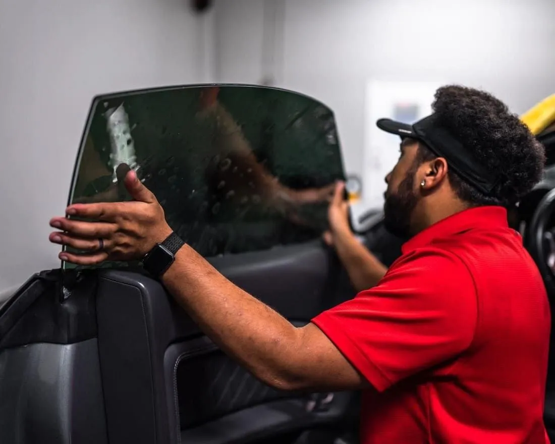 Technician installing window tint on a car door window