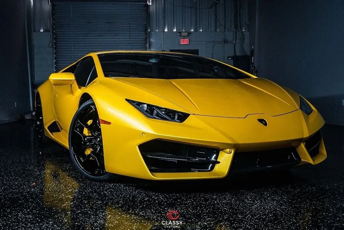 Yellow Lamborghini Huracan on wet pavement at night