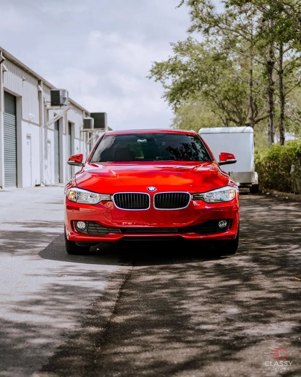 Red BMW sedan in front of an open shop bay