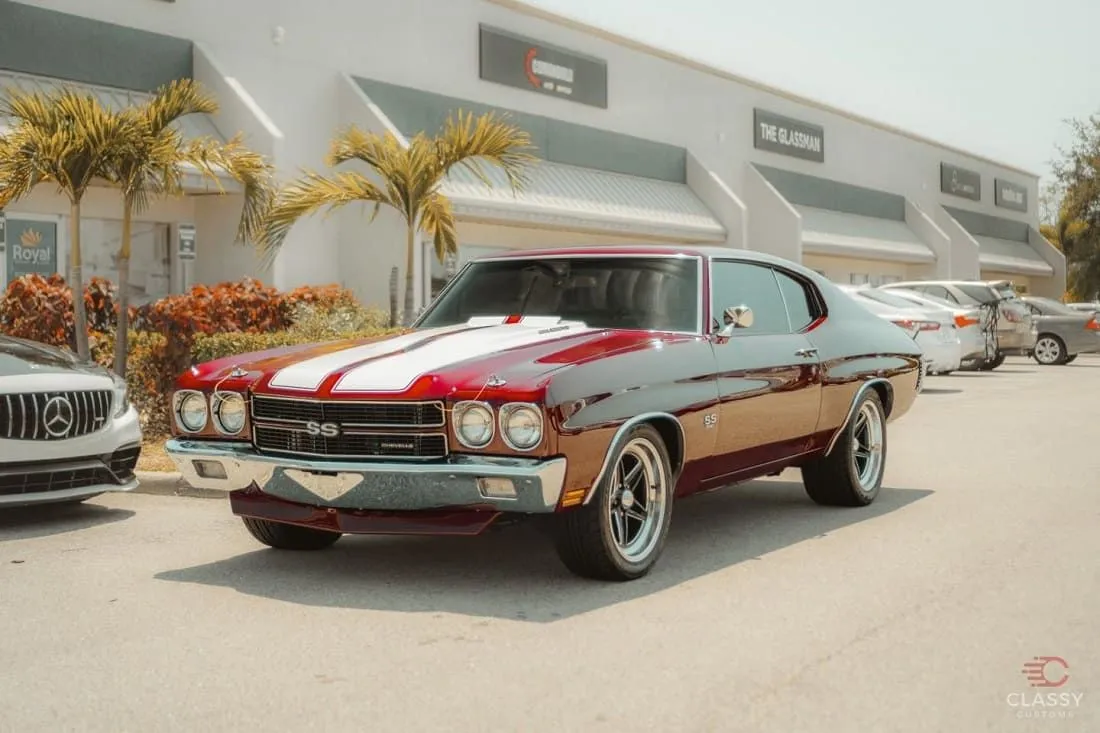 Classic red Chevrolet Chevelle with white stripes outside the shop