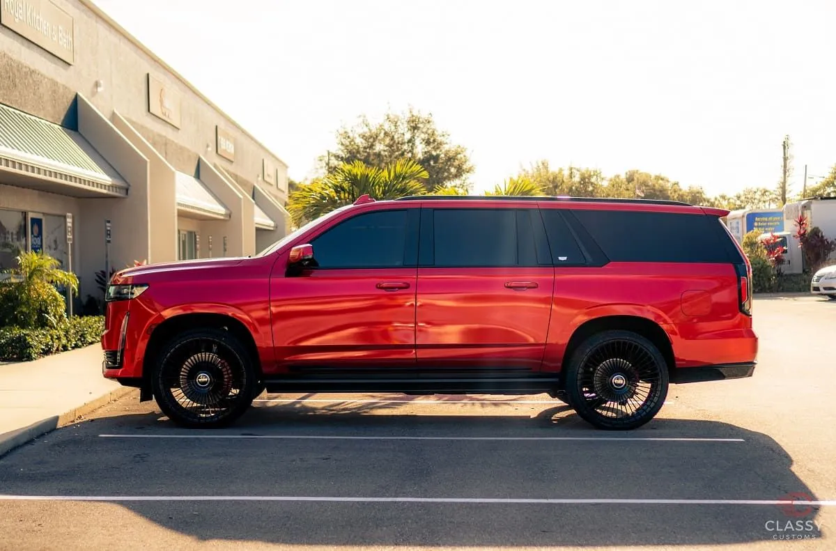 Red full-size SUV with a custom wrap outside the shop