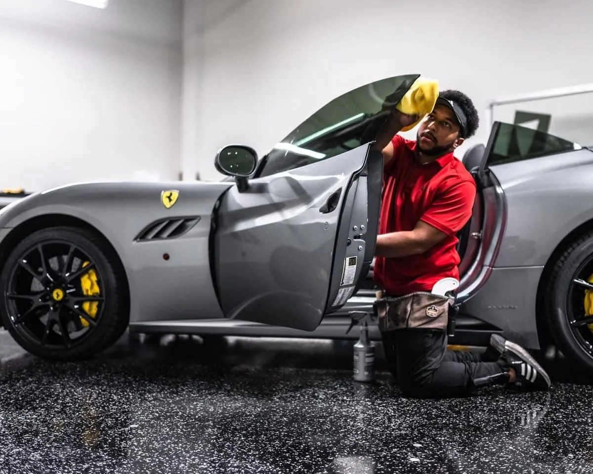 Technician tinting a gray Ferrari inside the shop