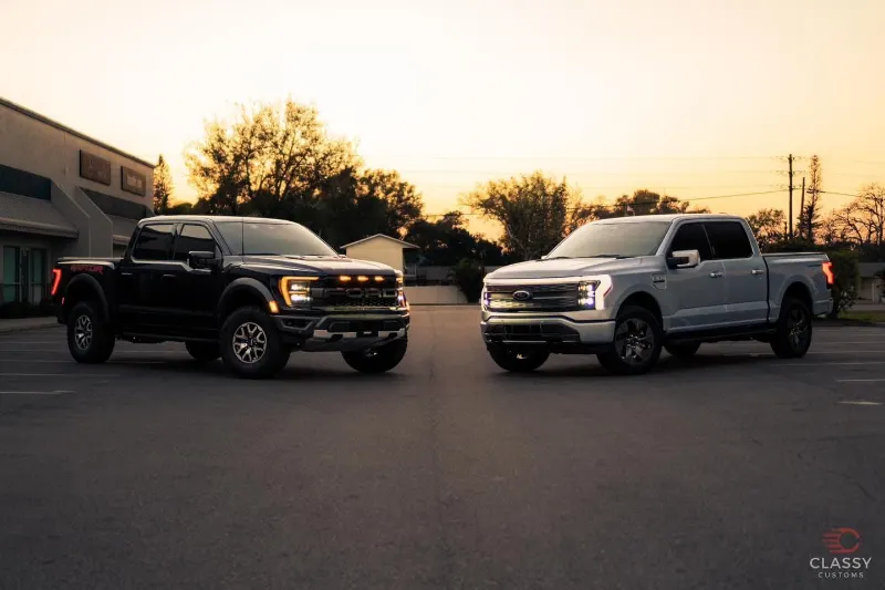 Black and white pickup trucks parked side by side at sunset