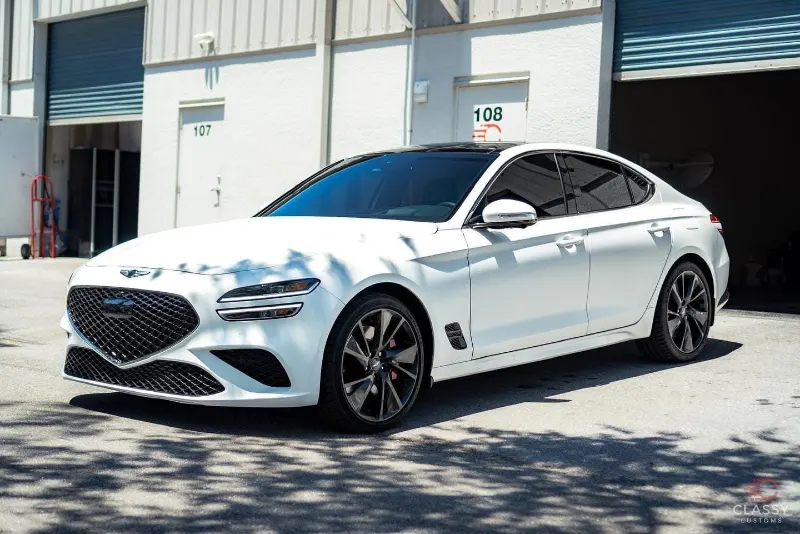 White Genesis sedan in front of the shop bay
