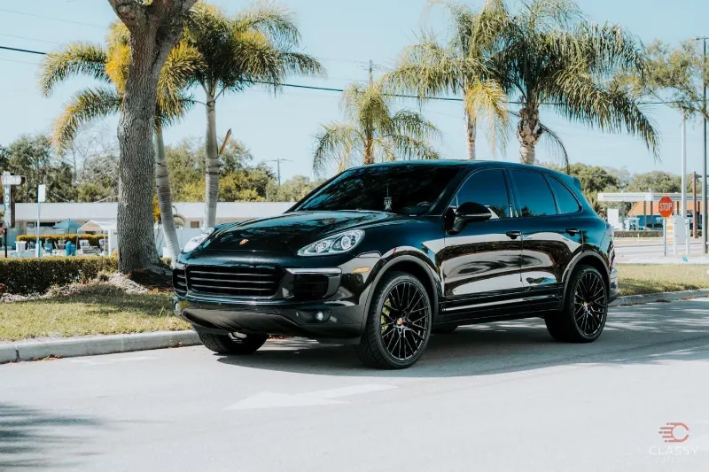 Black Porsche Cayenne under palm trees